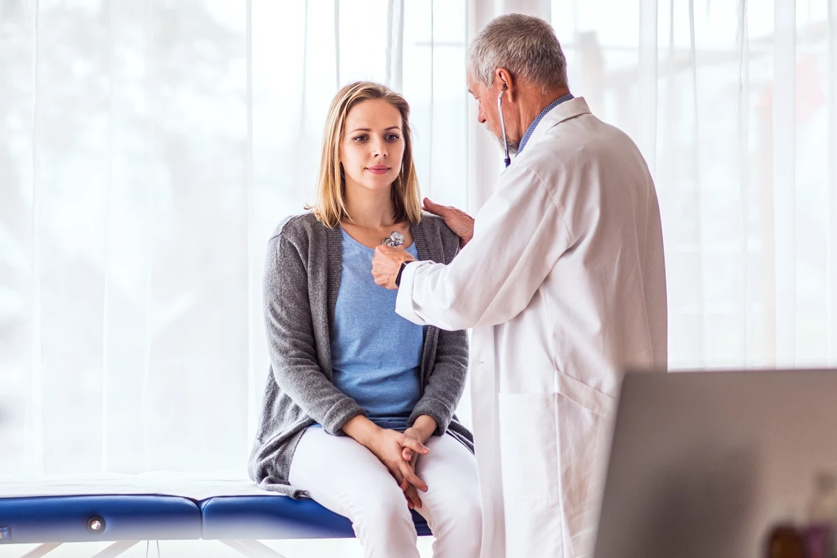 ärztliche Rücksprache Sport und Pollenallergie Eine weibliche Person wird von einem Arzt abgehört