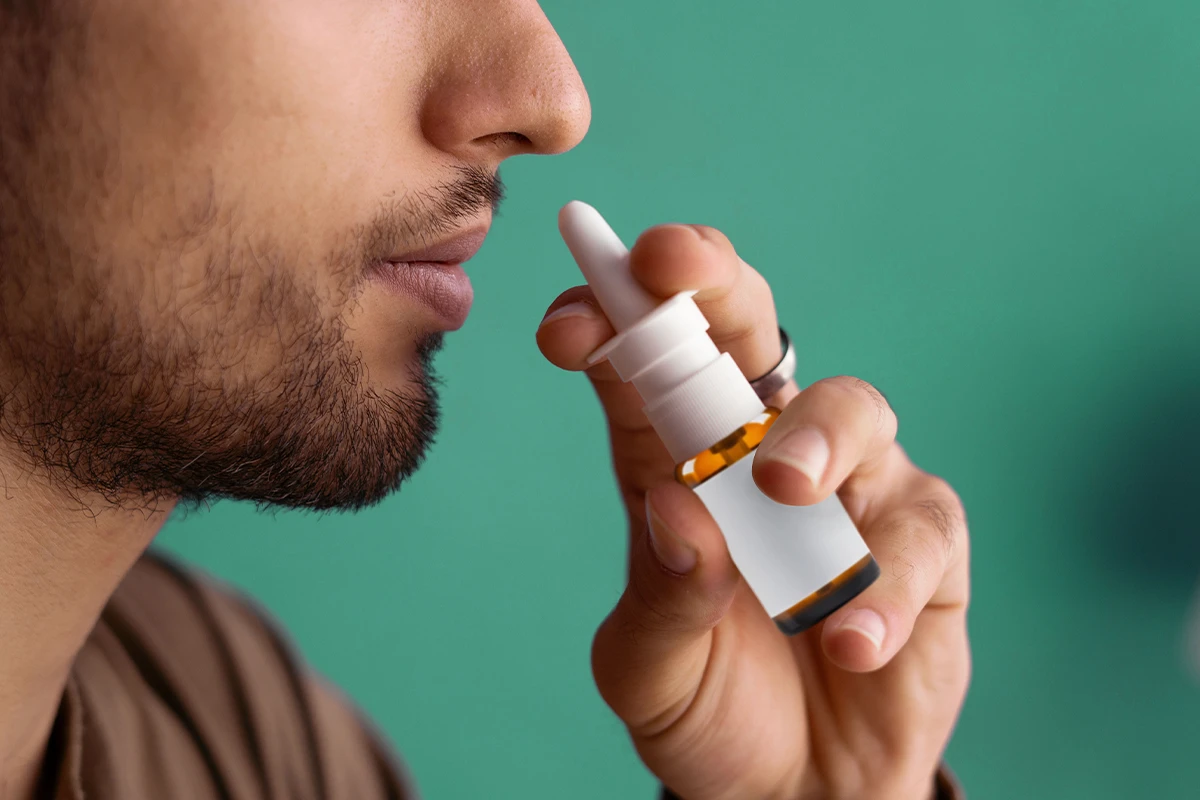 Eine männliche Person verabreicht sich ein Nasenspray