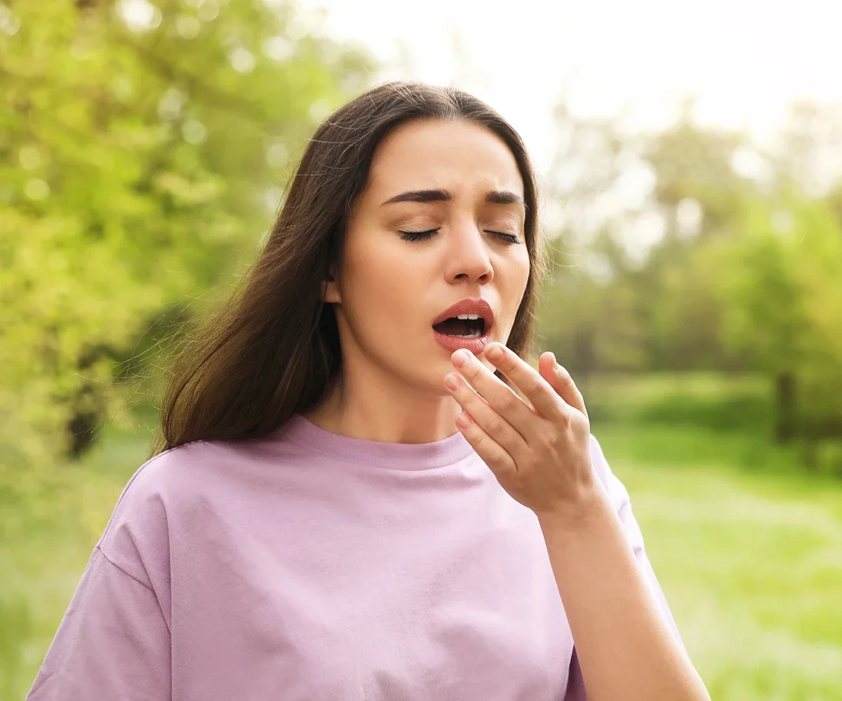 Eine weibliche Person beim Nießen in der Natur