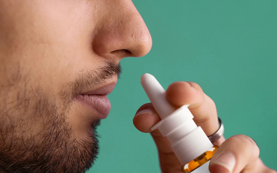 Behandlungsmoeglichkeiten Duoallerg Nasenspray Eine männliche Person hält sich ein Nasenspray an die Nase