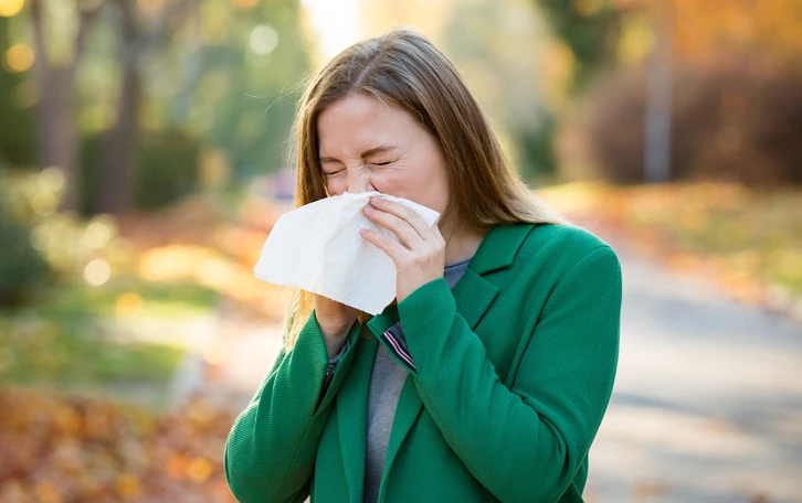 Eine weibliche Person in der Natur putzt sich die Nase