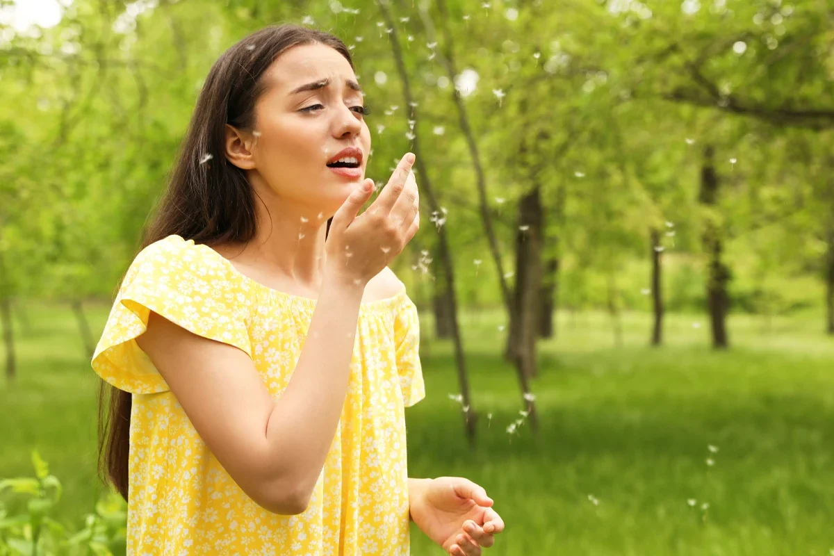 Eine weibliche Person mit Pollen um sich im Grünen