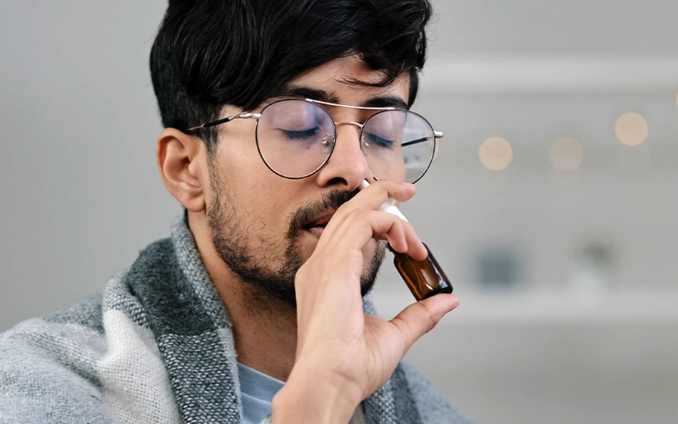 Eine männliche Person verabreicht sich ein Nasenspray