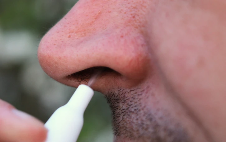 Eine männliche Person verabreicht sich Nasenspray