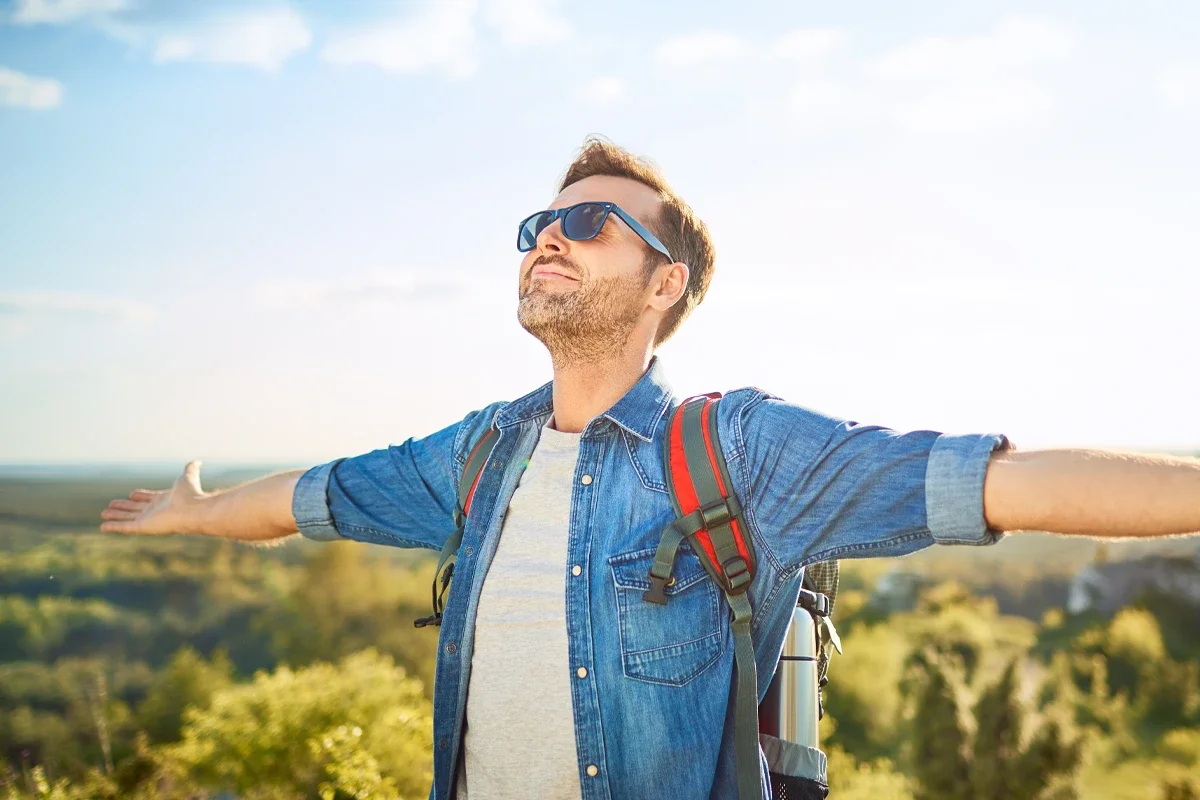 Schnell und lange Wirksam Heuschnupfen Eine männliche Person mit ausgebreiteten Armen mit Sonnenbrille auf und Rucksack auf
