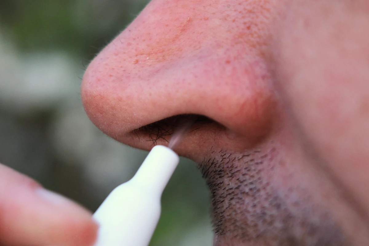 Eine männliche Person verabreicht sich Nasenspray