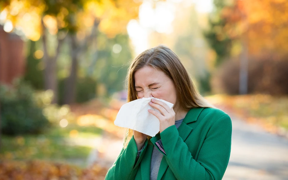 Eine weibliche Person in der Natur putzt sich die Nase