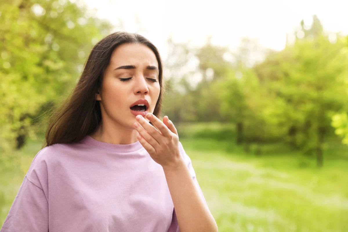 typische-symptome-der-pollenallergie Eine weibliche Person beim NieĂźen in der Natur
