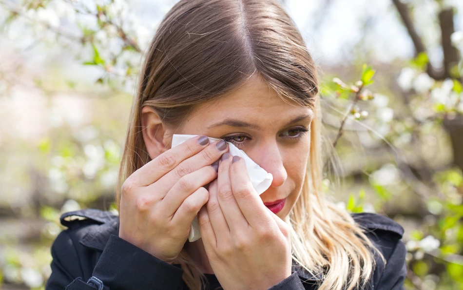 Typische Symptome Heuschnupfen tränende Augen Eine weibliche Person reibt mit einem Taschentuch unter ihrem Auge lang
