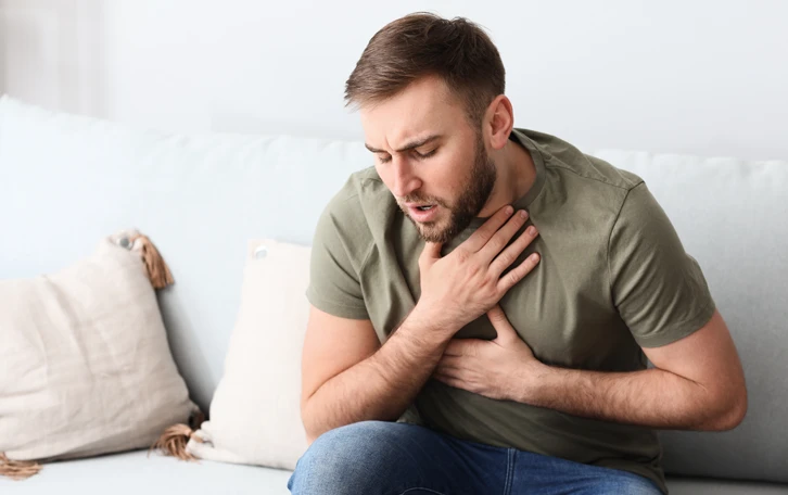 Typisches Symptom Pollenallergie Allergisches Asthma Eine männilche Person mit atemproblemen auf einer Couch sitzend
