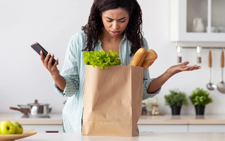 Typisches Symptom Pollenallergie Konzentrationsstörung Eine weibliche Person mit einer Tüte auf einer Arbeitsanrichte mit Salat und Brot aus der Tüte schauend
