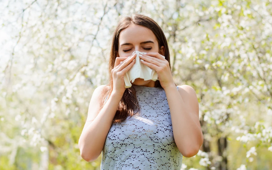 Eine weibliche Person in der Natur beim Nase putzen