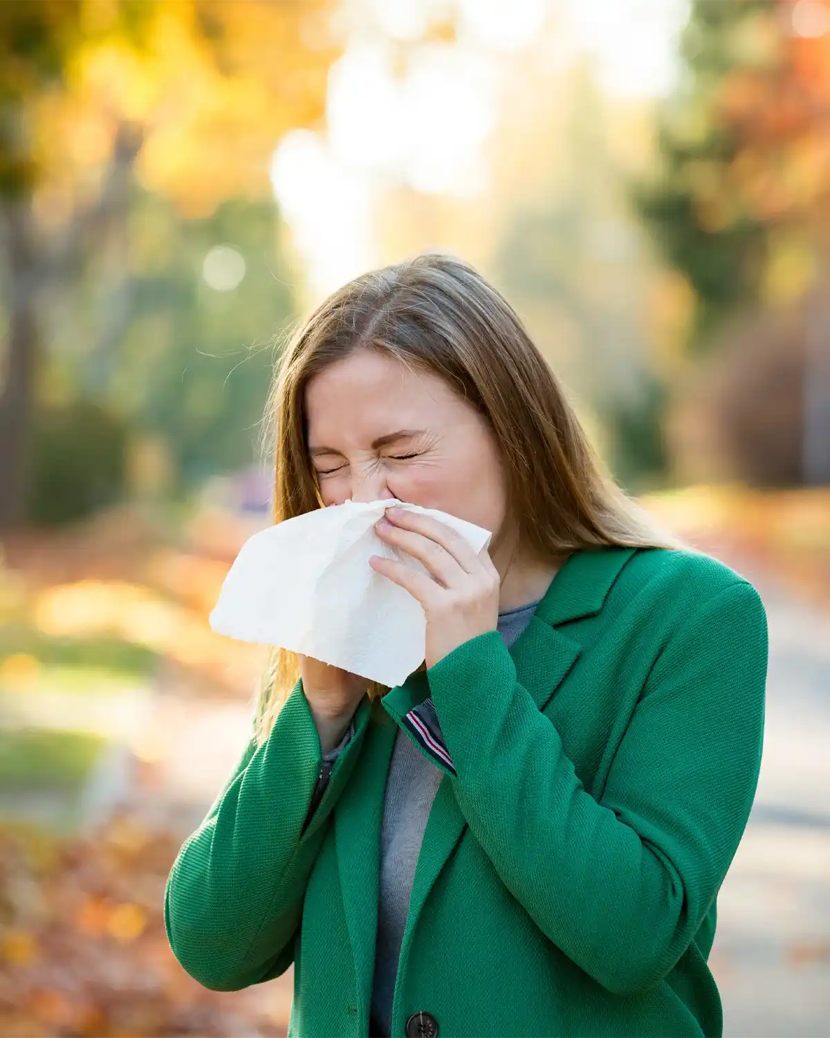 Eine weibliche Person in der Natur putzt sich die Nase