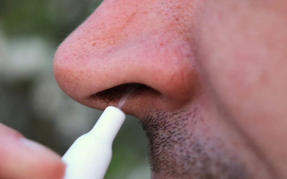 Vorteile der Kombinationstherapie mir Duoallerg Eine männliche Person verabreicht sich Nasenspray