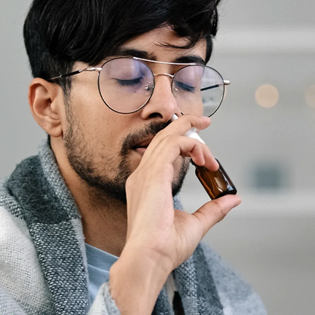 Eine männliche Person verabreicht sich ein Nasenspray