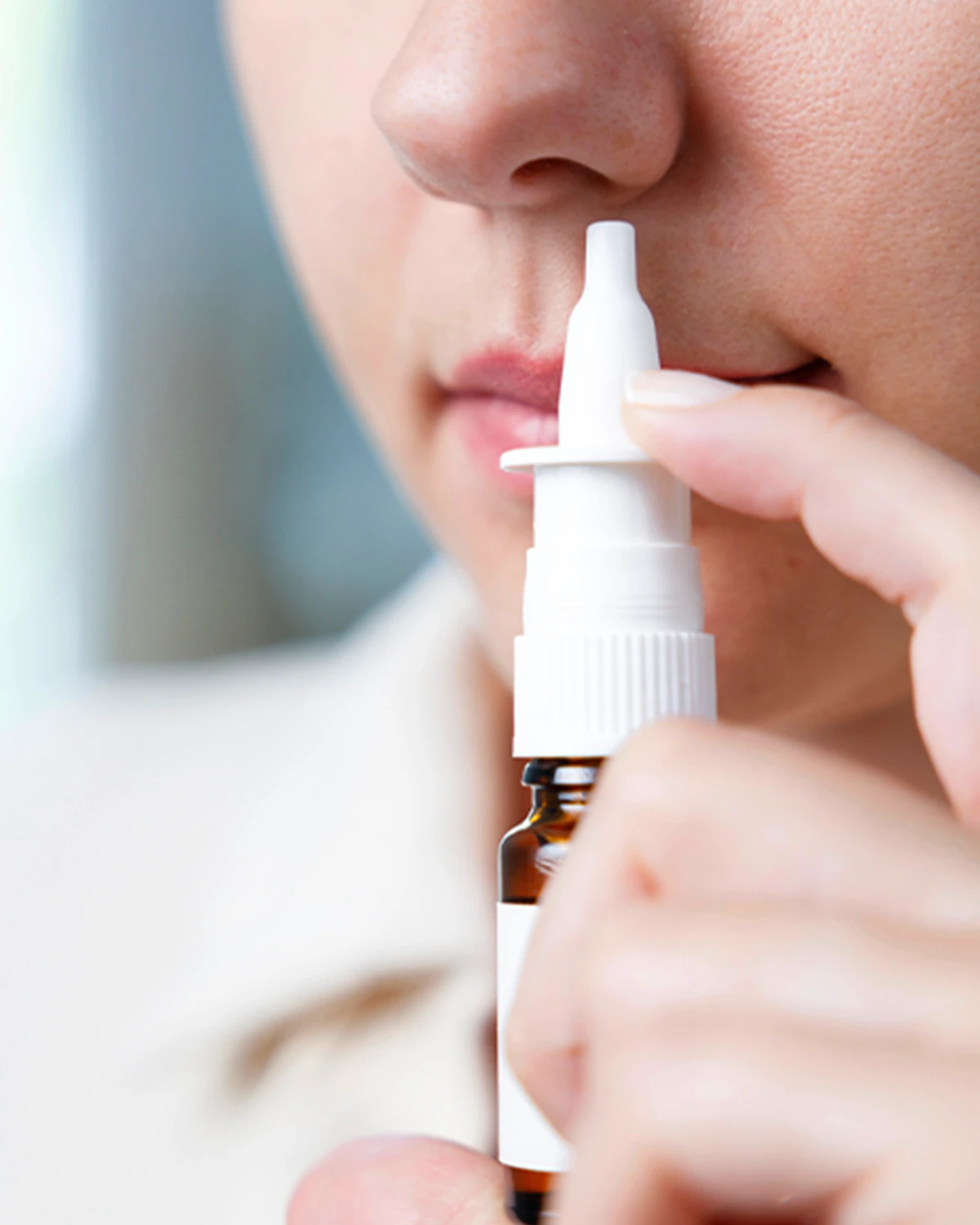 Zwei in Eins Nasenspray lindert Heuschnupfen Eine weibliche Person hält sich ein Nasenspray an die Nase